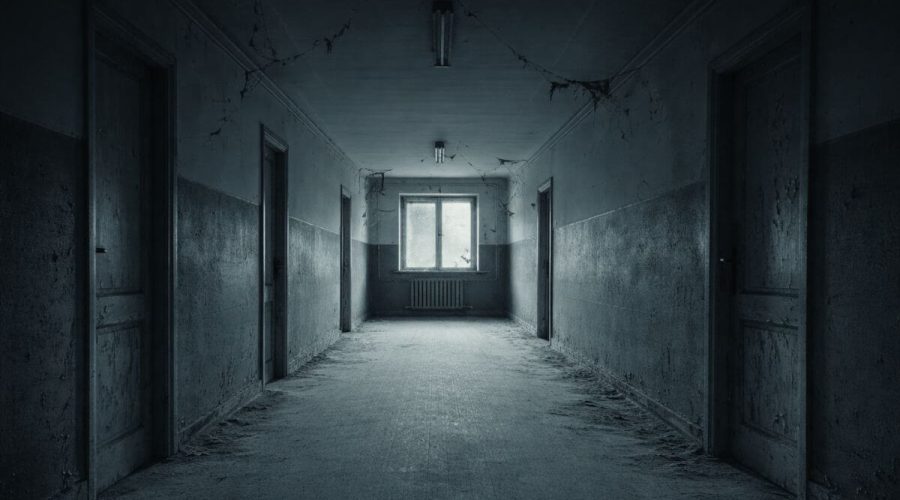 Wide abandoned apartment corridor with peeling walls, dusty floor, and cold blue lighting.